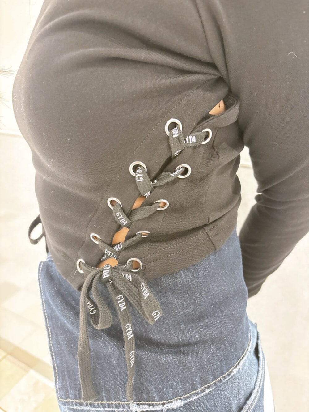 ブルー系のデニムパンツ、ブラック系のスニーカー、ブラック系のTシャツ/カットソーを着用したレディースの秋コーディネートの5枚目の写真