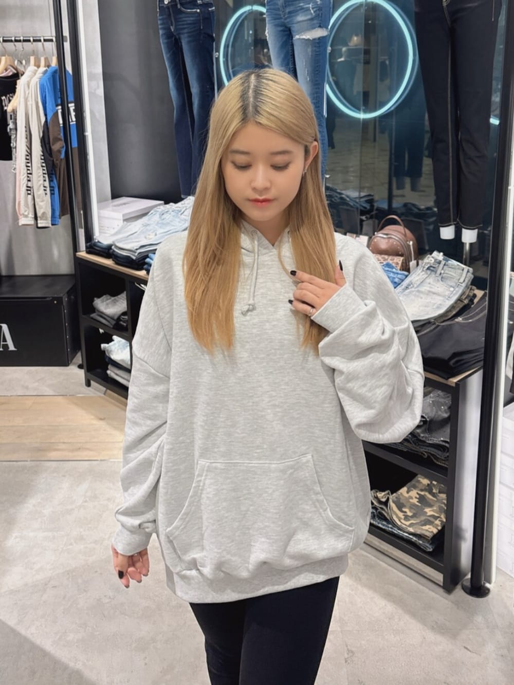 ブラック系のデニムパンツ、ブラック系のブーツ、グレー系のパーカーを着用したレディースの秋コーディネートの5枚目の写真