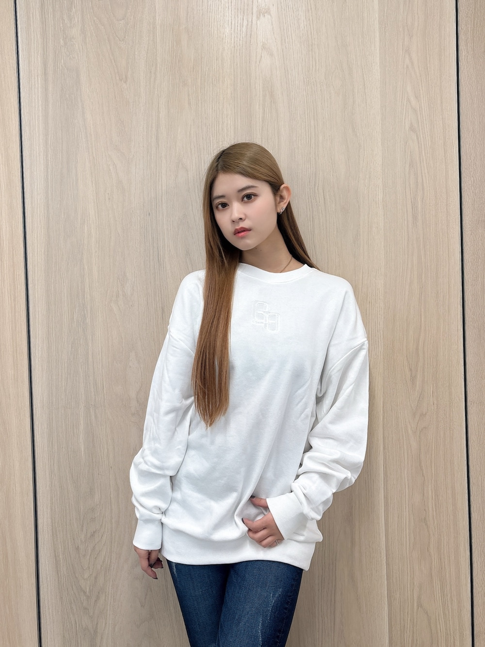 ホワイト系のパーカー、ブルー系のデニムパンツ、ブラック系のブーツを着用したレディースの春コーディネートの4枚目の写真