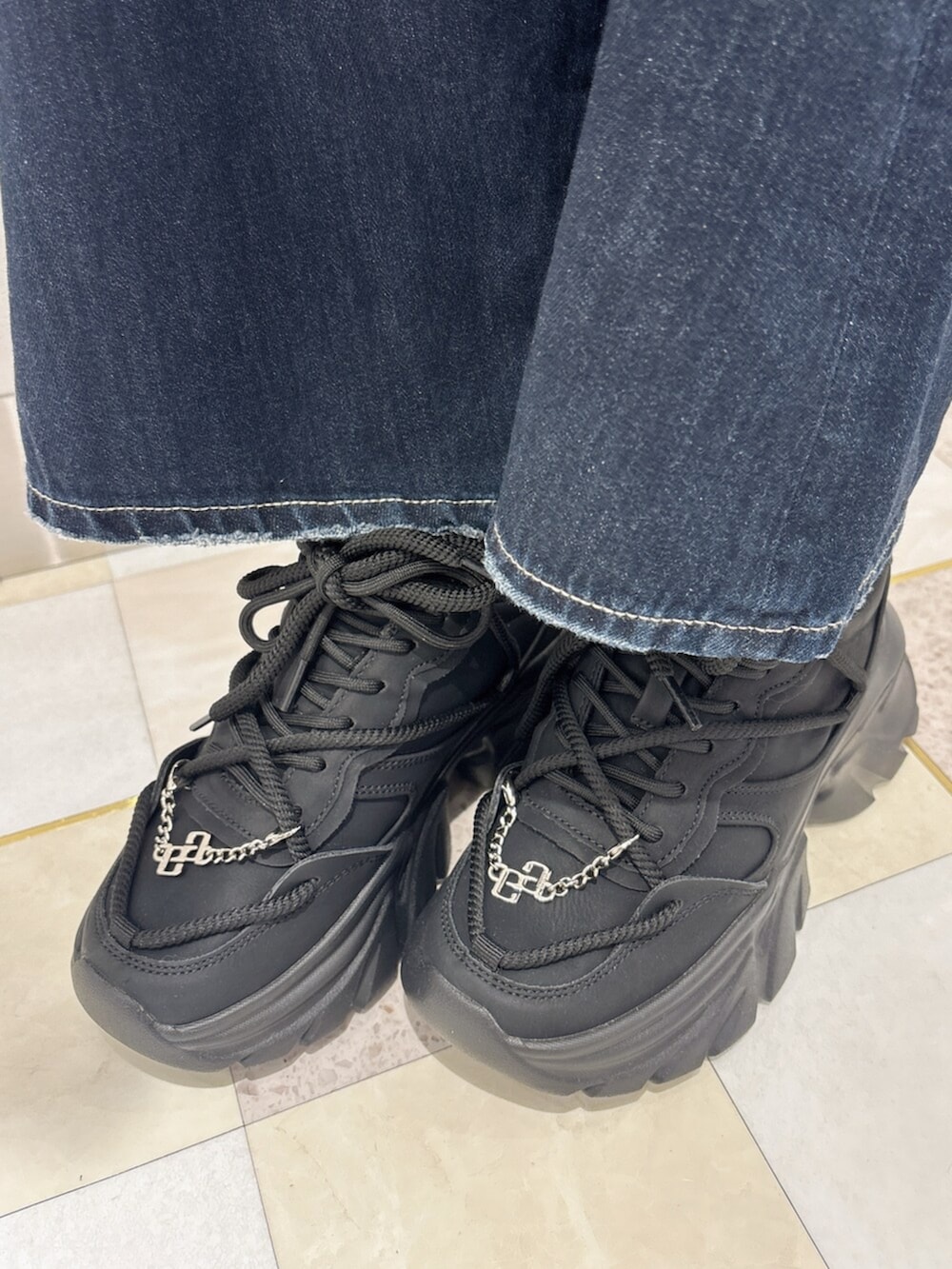ブラック系のニット/セーター、ブルー系のデニムパンツ、ブラック系のスニーカーを着用したレディースの夏コーディネートの8枚目の写真