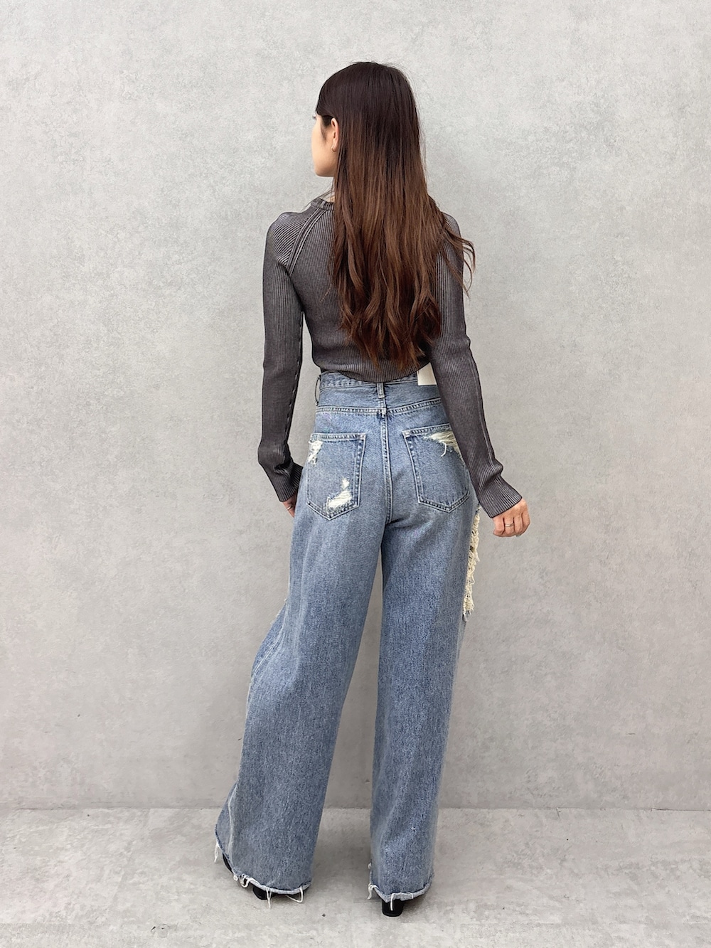 ブラック系のニット/セーター、ブルー系のデニムパンツ、ブラック系のサンダルを着用したレディースの夏コーディネートの3枚目の写真