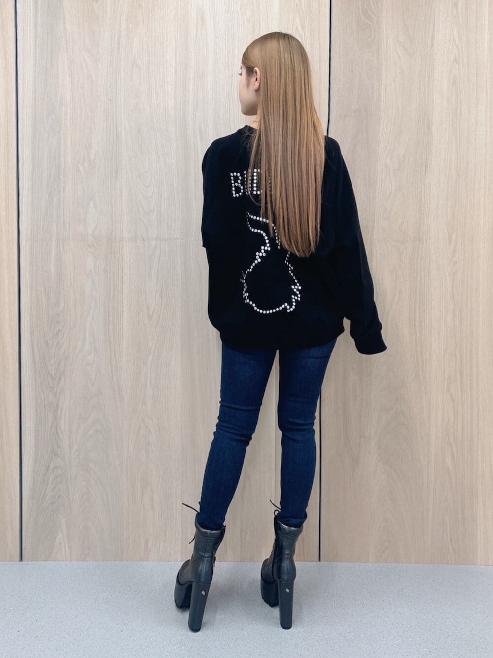 ブルー系のデニムパンツ、ブラック系のブーツ、ブラック系のスウェットを着用したレディースの春コーディネートの3枚目の写真