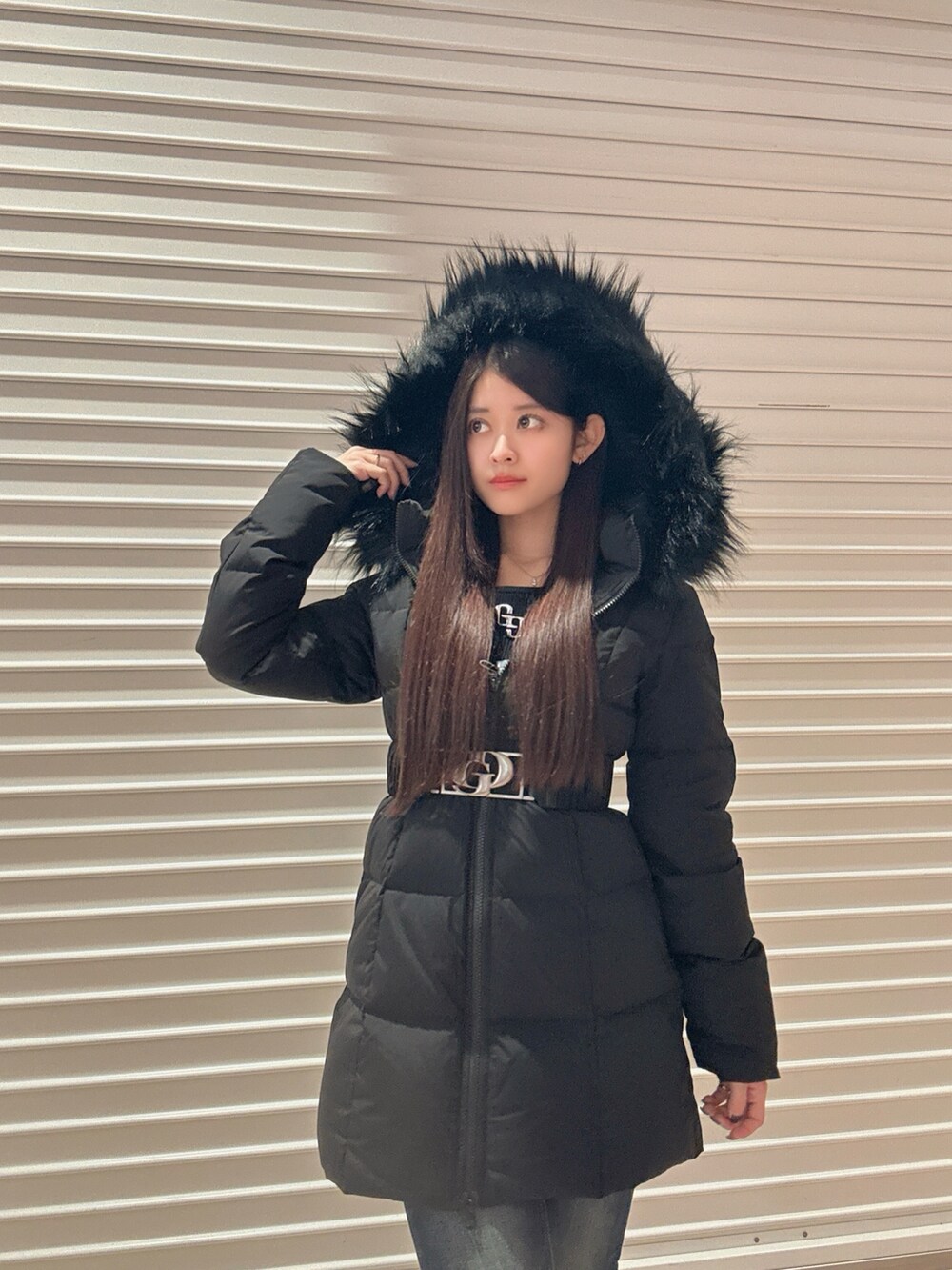 ブラック系のニット/セーター、ブラック系のダウンジャケット/コート、ブルー系のデニムパンツを着用したレディースの秋コーディネートの6枚目の写真