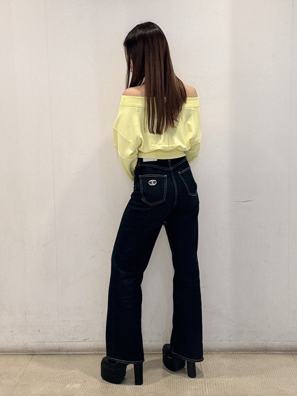 イエロー系のスウェット、ブルー系のデニムパンツ、ブラック系のブーツを着用したレディースの冬コーディネートの2枚目の写真