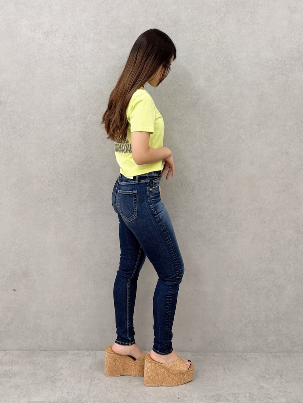 ブルー系のデニムパンツ、グリーン系のTシャツ/カットソー、ホワイト系のサンダルを着用したレディースの夏コーディネートの2枚目の写真