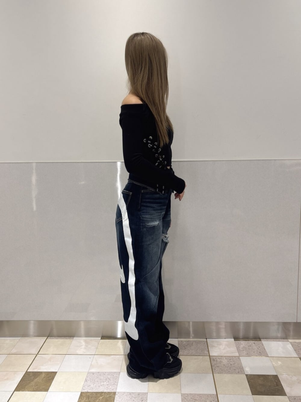 ブルー系のデニムパンツ、ブラック系のスニーカー、ブラック系のTシャツ/カットソーを着用したレディースの秋コーディネートの2枚目の写真