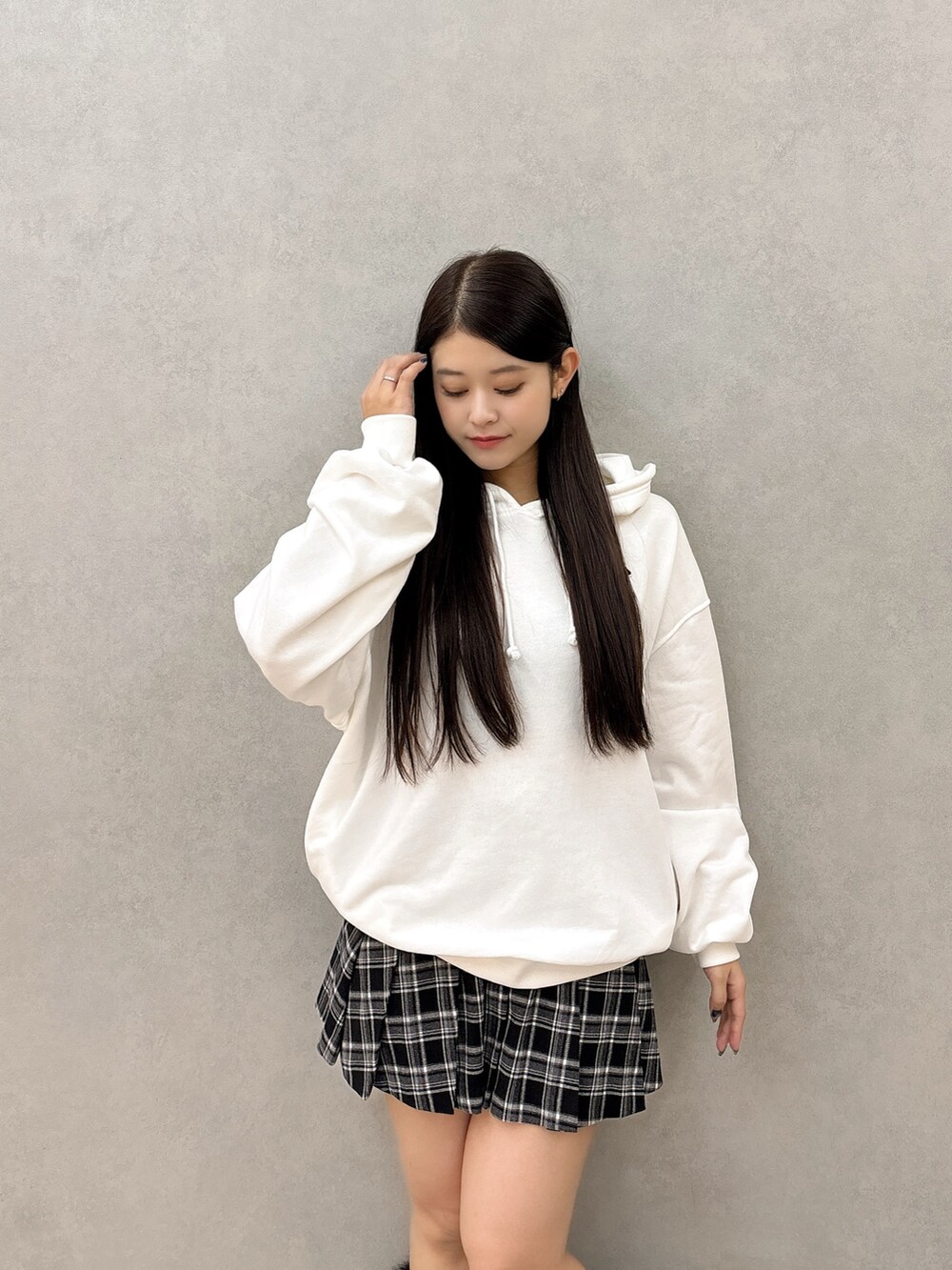 ホワイト系のパーカー、ブラック系のスカート、ブラック系のブーツを着用したレディースの秋コーディネートの4枚目の写真