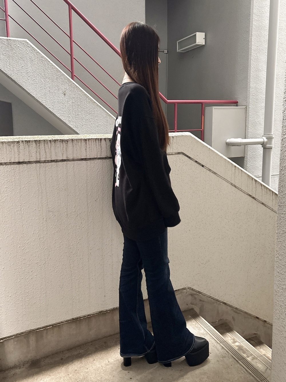 ブラック系のスウェット、ブルー系のデニムパンツ、ブラック系のブーツを着用したレディースの秋コーディネートの2枚目の写真