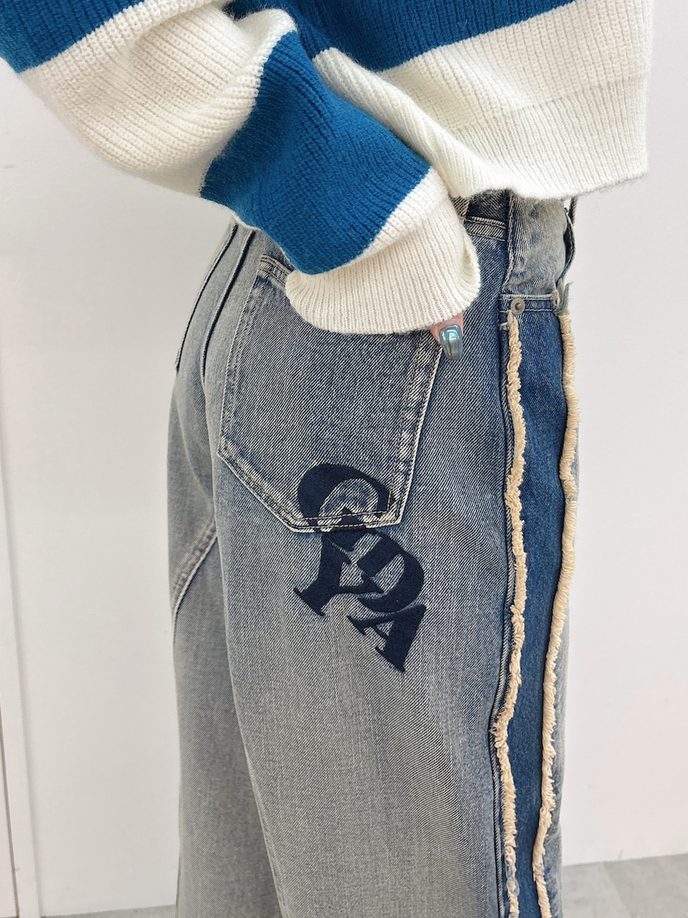 ブルー系のニット/セーター、ブルー系のデニムパンツ、ブラック系のブーツを着用したレディースの秋コーディネートの6枚目の写真