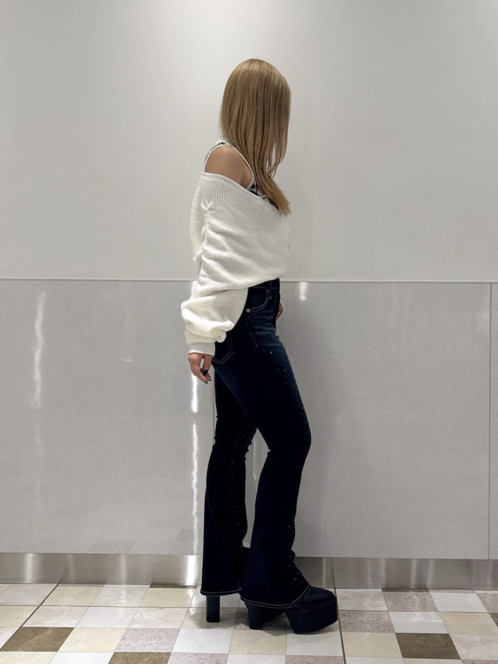 ブラック系のブーツ、ホワイト系のニット/セーター、ブルー系のデニムパンツを着用したレディースの秋コーディネートの2枚目の写真