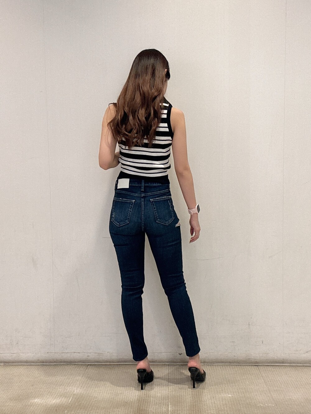 ホワイト系のニット/セーター、ブルー系のデニムパンツ、ブラック系のパンプスを着用したレディースの春コーディネートの3枚目の写真