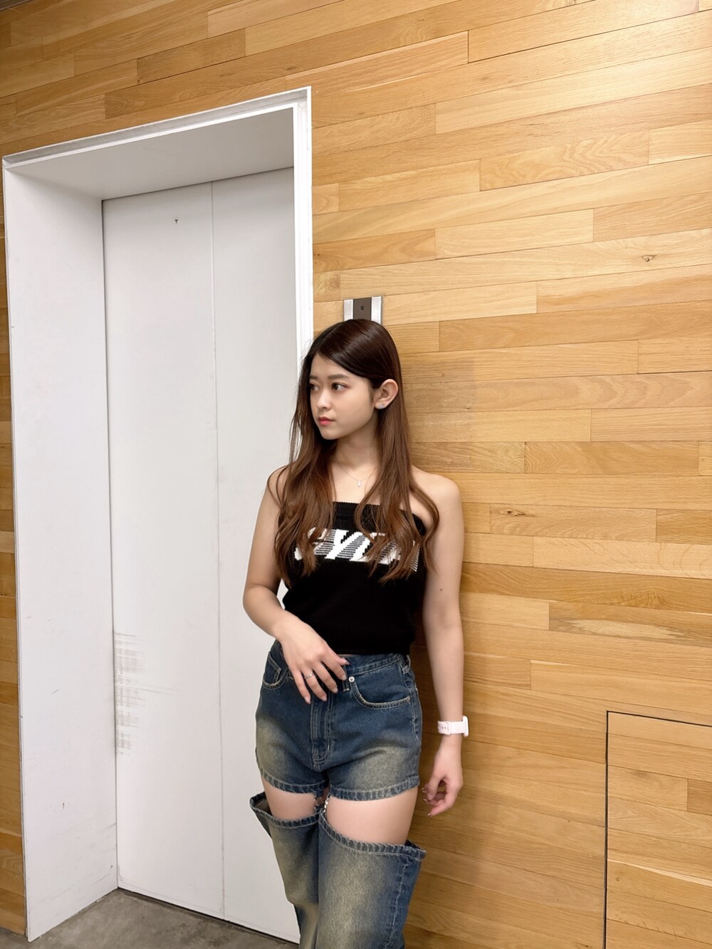 ブラック系のニット/セーター、ブルー系のデニムパンツ、ブラック系のサンダルを着用したレディースの夏コーディネートの4枚目の写真