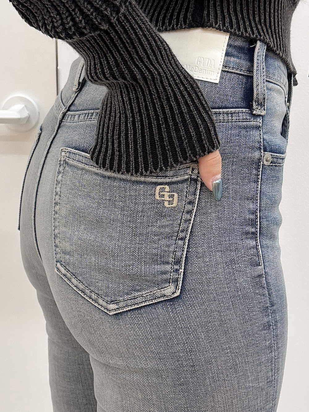 ブラック系のブーツ、ブラック系のニット/セーター、ブルー系のデニムパンツを着用したレディースの秋コーディネートの5枚目の写真