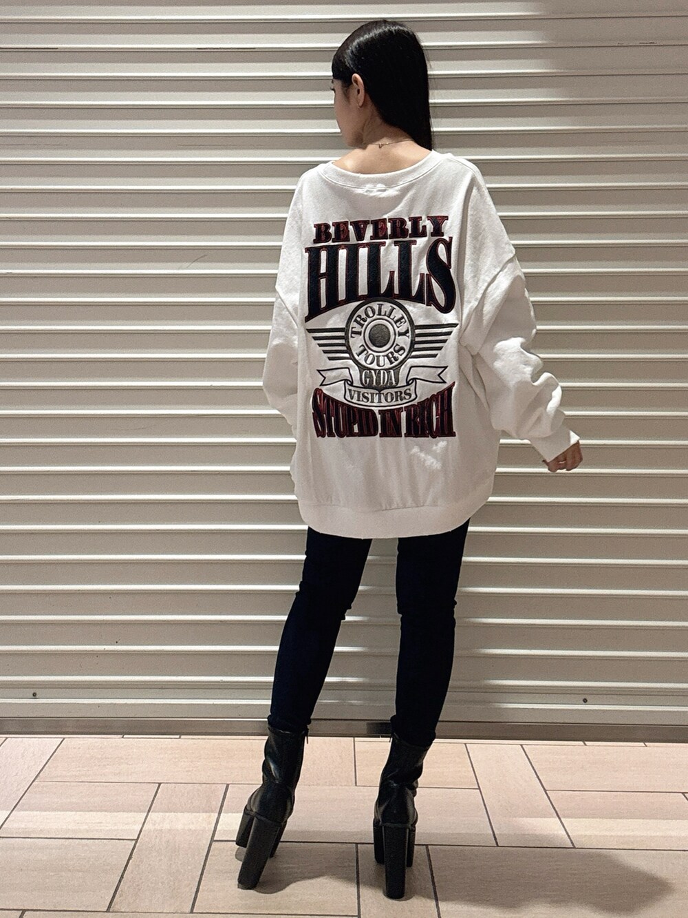 ホワイト系のスウェット、ブルー系のデニムパンツ、ブラック系のブーツを着用したレディースの秋コーディネートの3枚目の写真