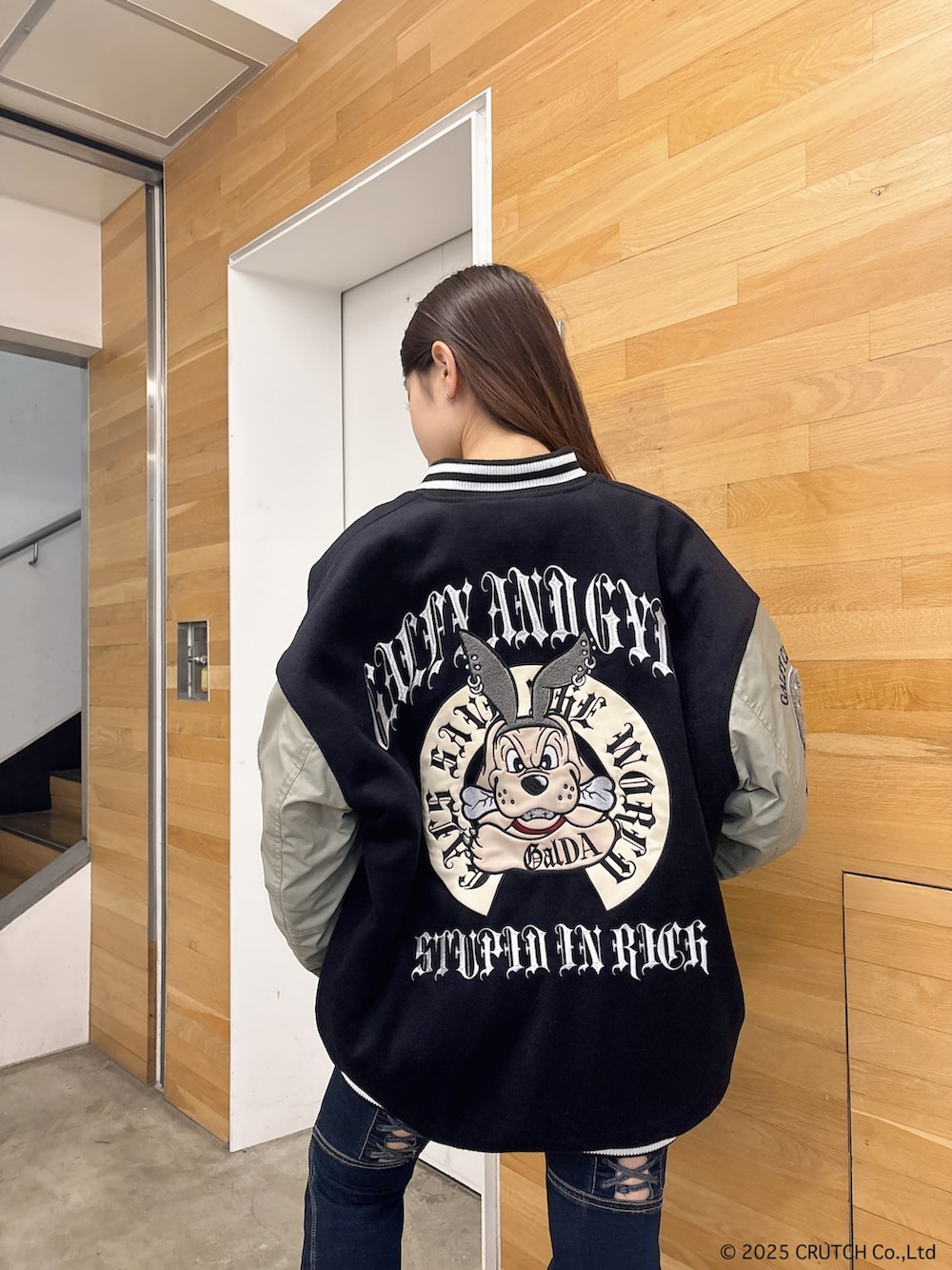 ブラック系のスタジャン、ホワイト系のニット/セーター、ブルー系のデニムパンツを着用したレディースの秋コーディネートの5枚目の写真