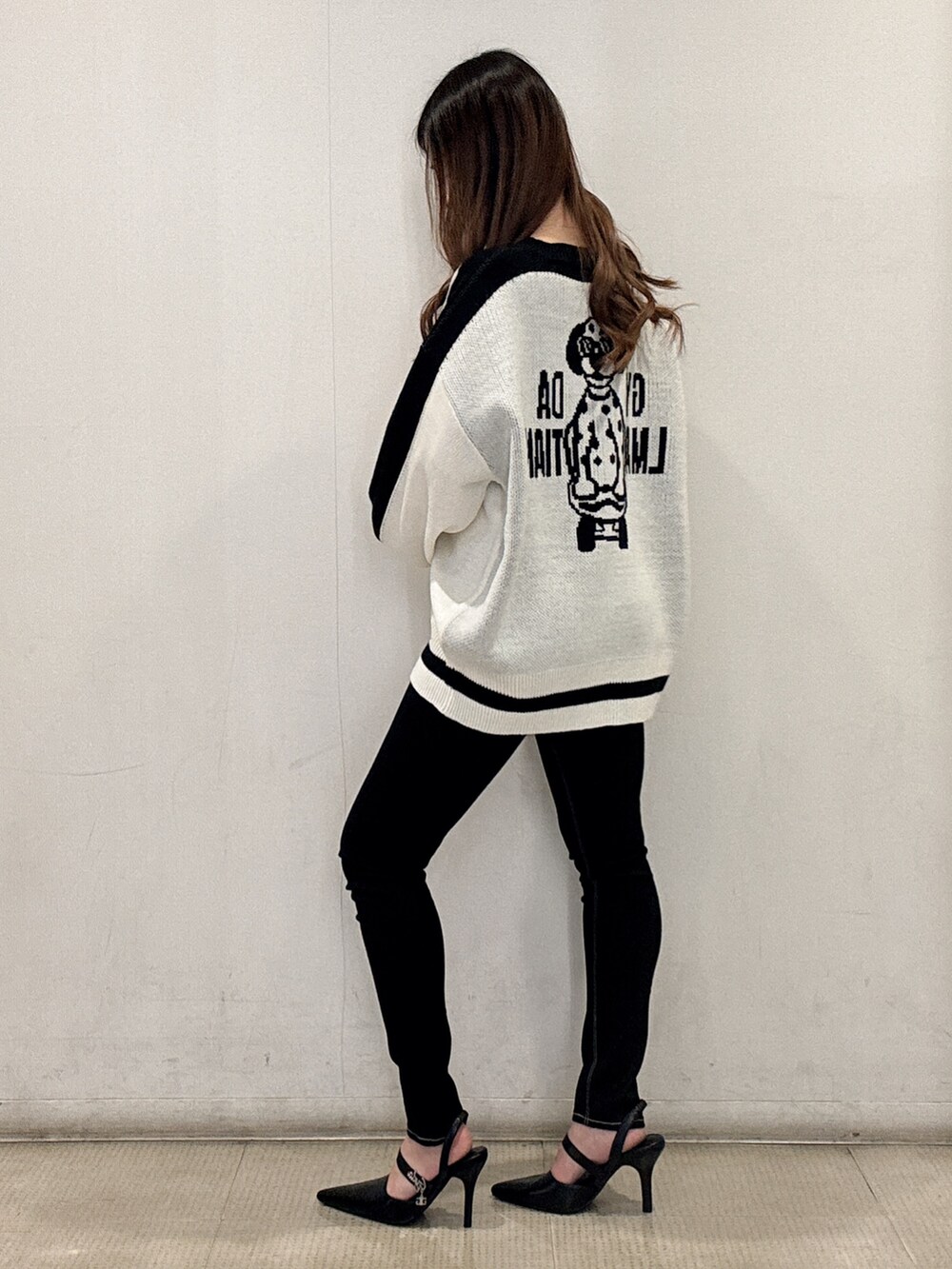 ホワイト系のニット/セーター、ブラック系のデニムパンツ、ブラック系のパンプスを着用したレディースの春コーディネートの3枚目の写真