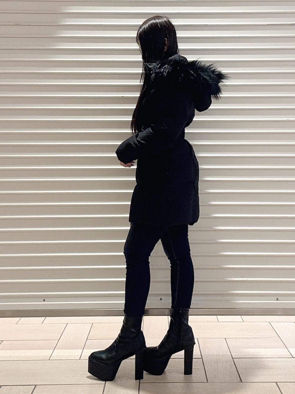 ブラック系のニット/セーター、ブラック系のダウンジャケット/コート、ブルー系のデニムパンツを着用したレディースの秋コーディネートの3枚目の写真