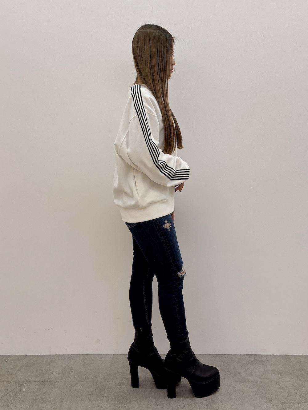 ホワイト系のスウェット、ブルー系のデニムパンツ、ブラック系のブーツを着用したレディースの冬コーディネートの2枚目の写真