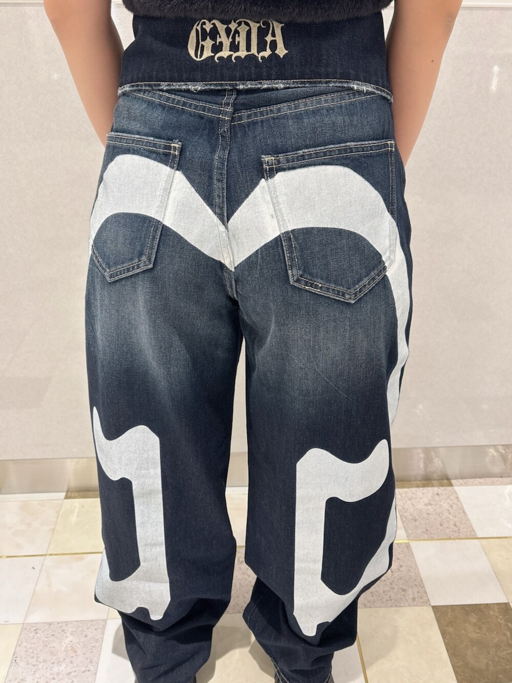 ブラック系のニット/セーター、ブルー系のデニムパンツ、ブラック系のスニーカーを着用したレディースの夏コーディネートの7枚目の写真