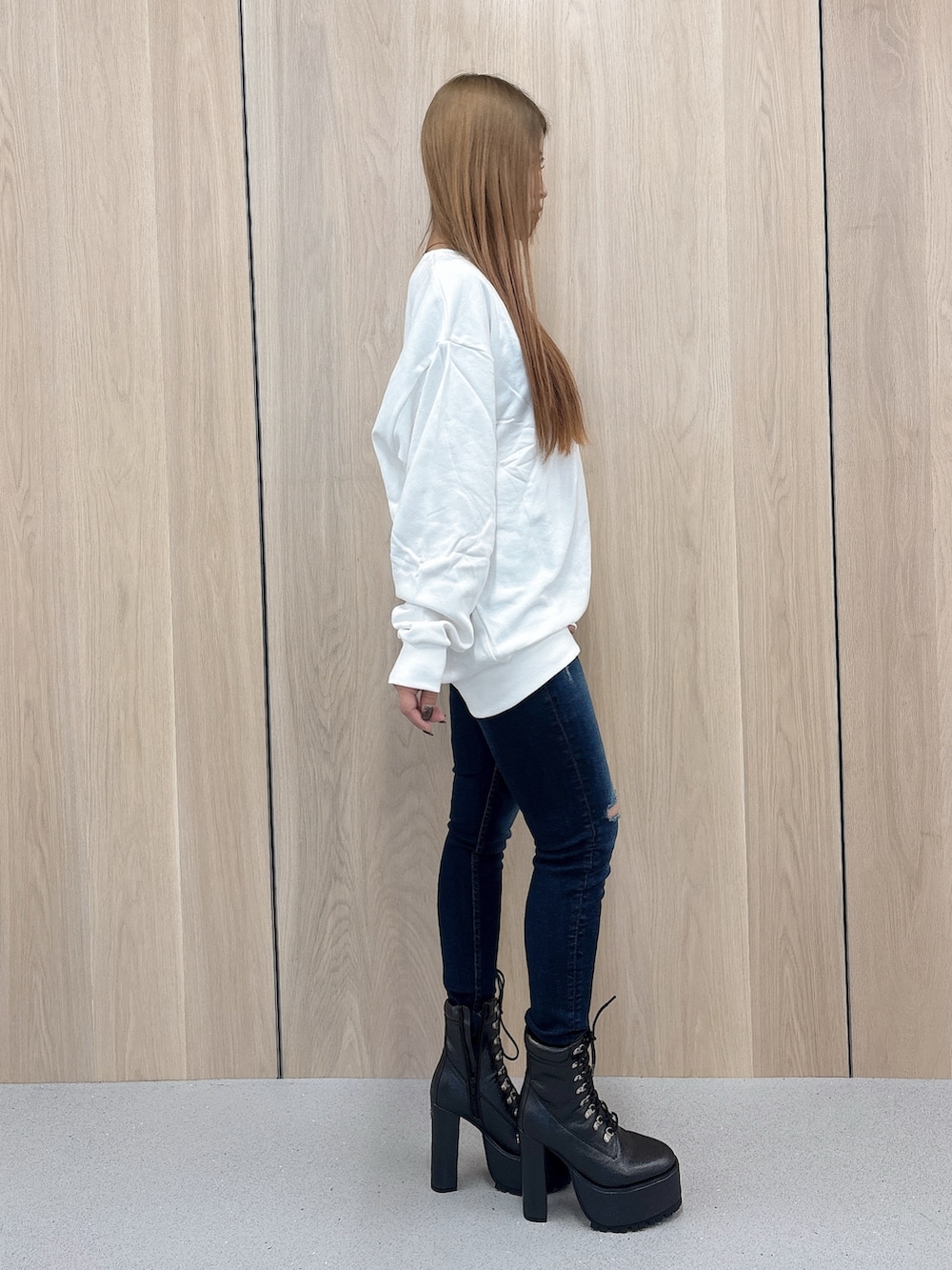 ホワイト系のパーカー、ブルー系のデニムパンツ、ブラック系のブーツを着用したレディースの春コーディネートの2枚目の写真