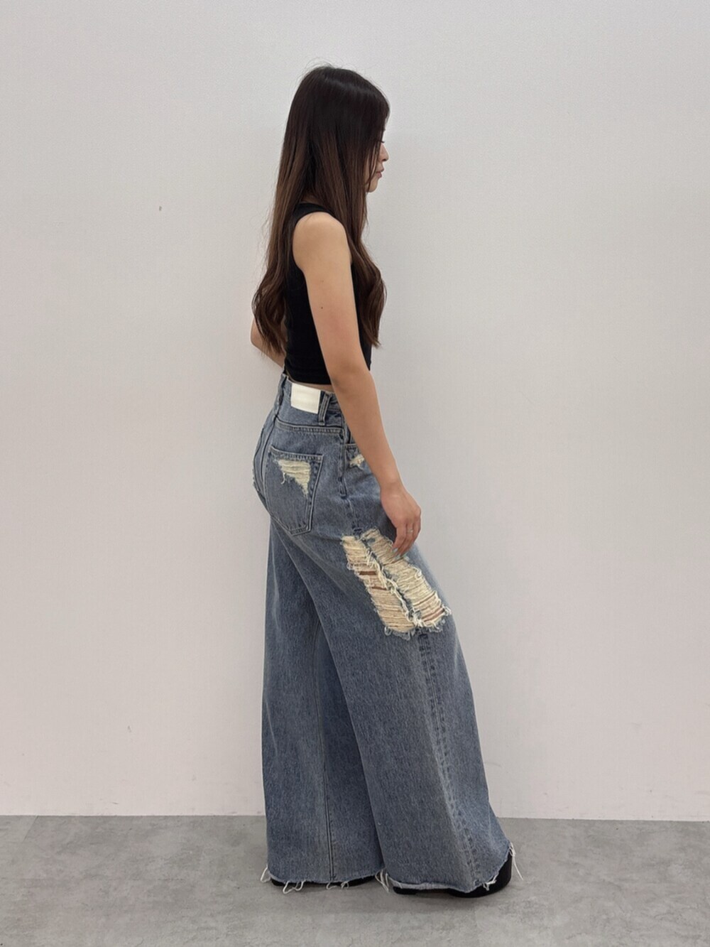 ブラック系のサンダル、ブルー系のデニムパンツ、ブラック系のタンクトップを着用したレディースの夏コーディネートの2枚目の写真