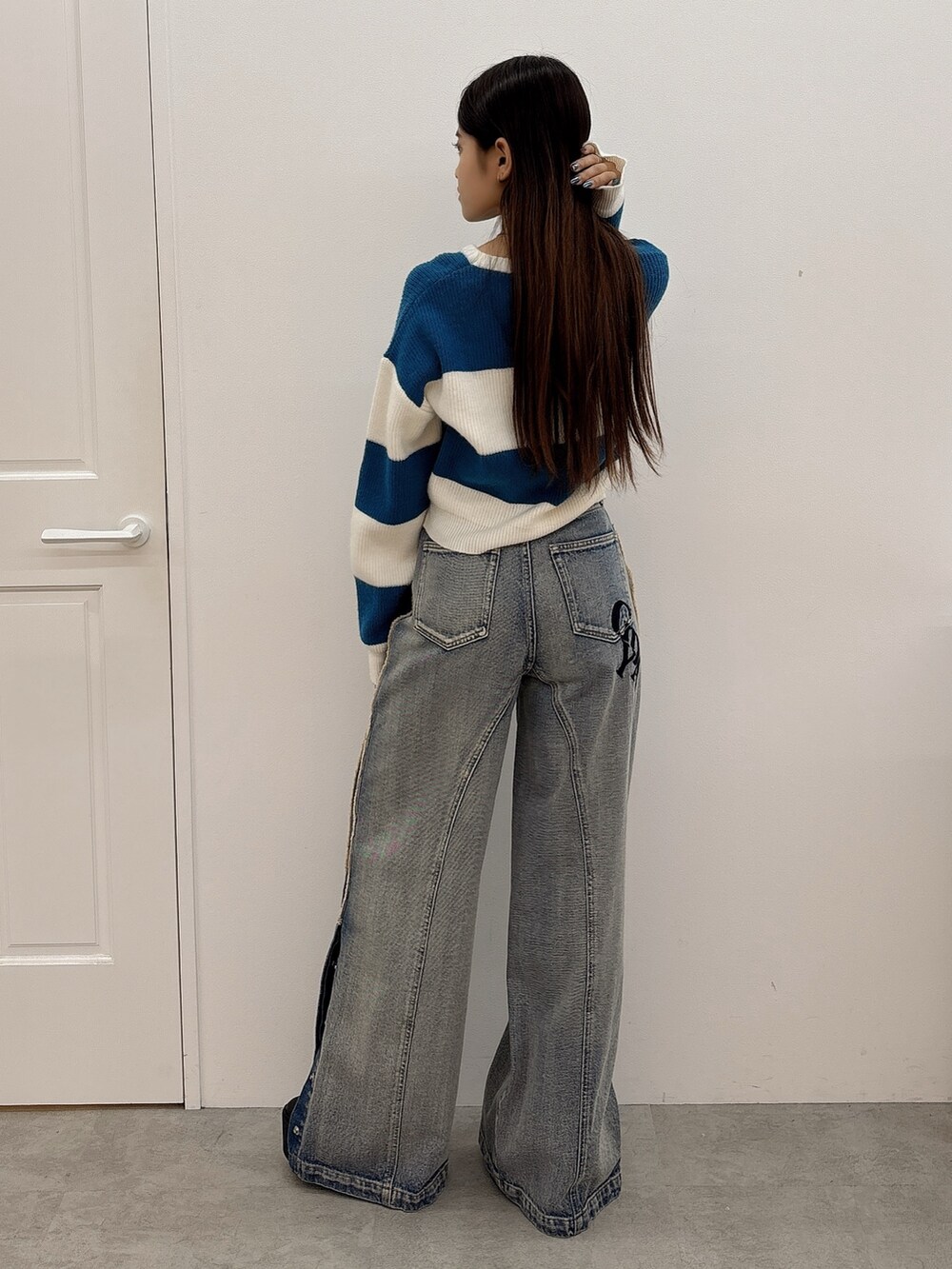 ブルー系のニット/セーター、ブルー系のデニムパンツ、ブラック系のブーツを着用したレディースの秋コーディネートの3枚目の写真