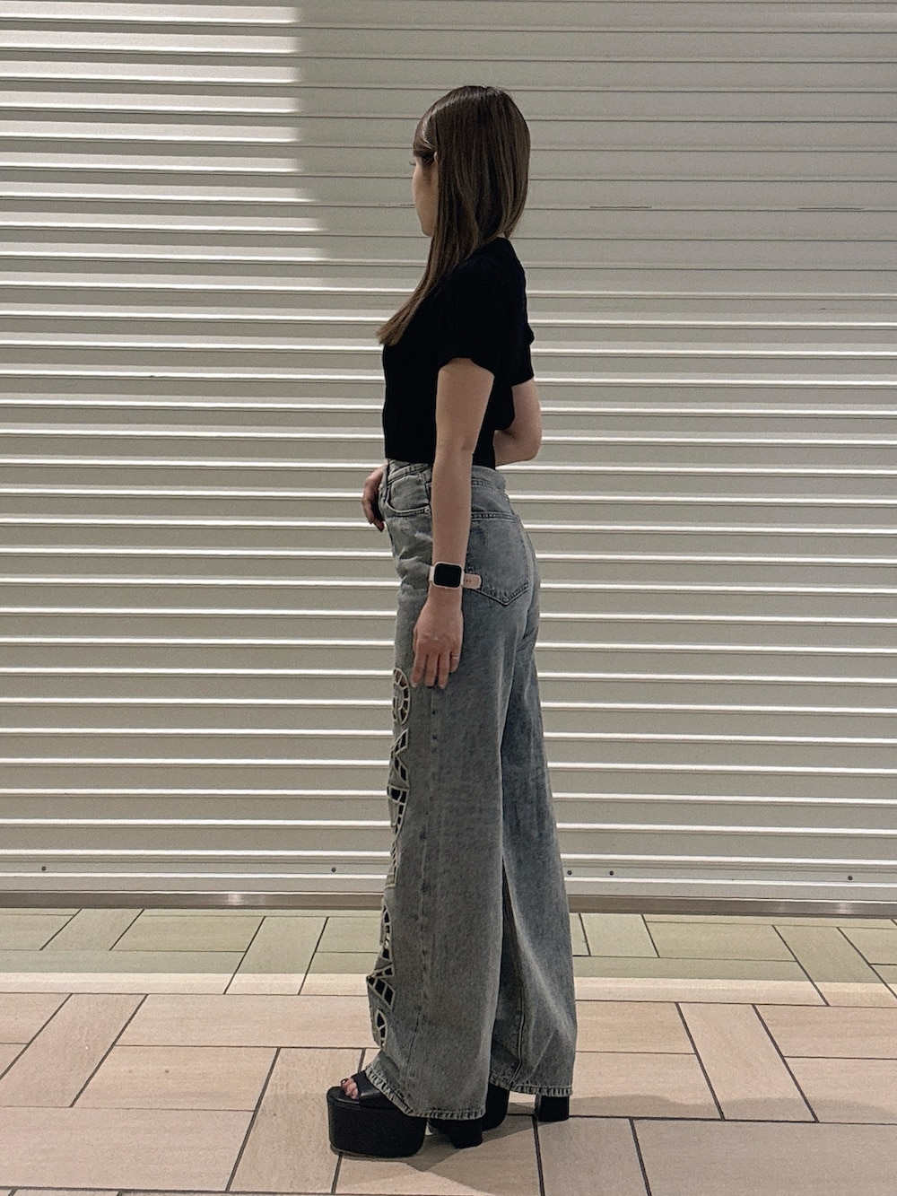 ブラック系のTシャツ/カットソー、ブルー系のデニムパンツ、ブラック系のサンダルを着用したレディースの春コーディネートの2枚目の写真