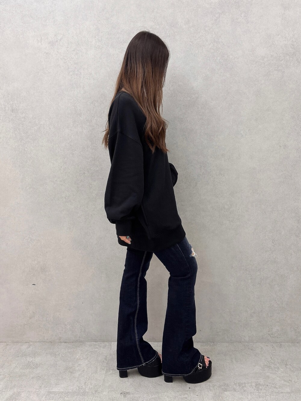 ブラック系のスウェット、ブルー系のデニムパンツ、ブラック系のサンダルを着用したレディースの夏コーディネートの2枚目の写真