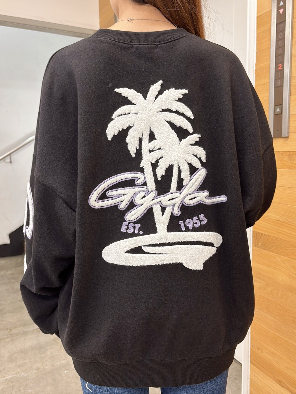 ブラック系のスウェット、ブルー系のデニムパンツ、ブラック系のブーツを着用したレディースの夏コーディネートの6枚目の写真