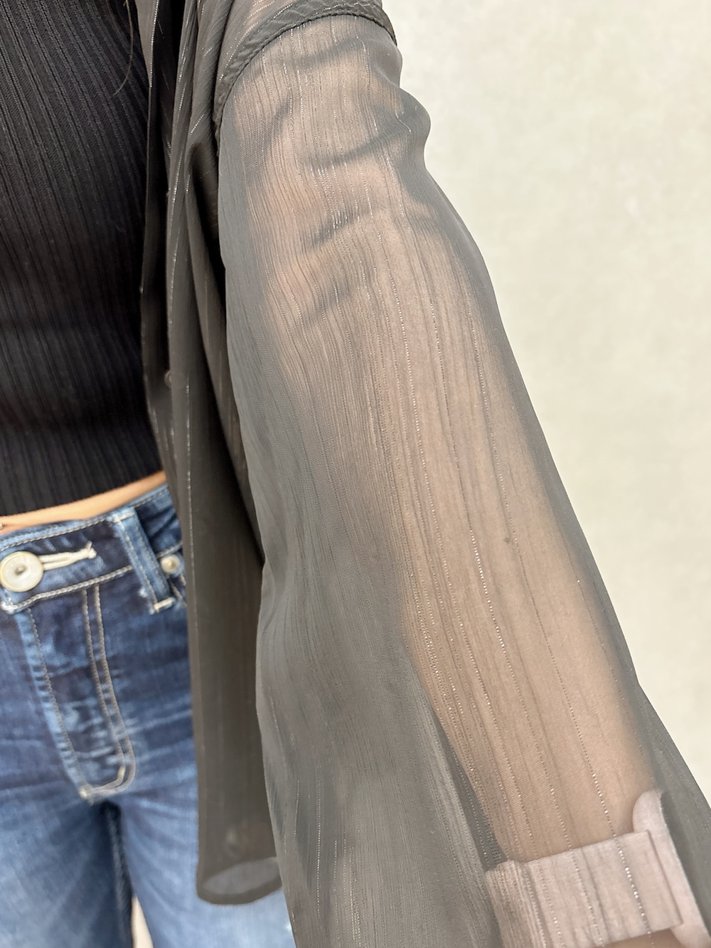 ブラック系のシャツ/ブラウス、ブラック系のTシャツ/カットソー、ブルー系のデニムパンツを着用したレディースの冬コーディネートの6枚目の写真