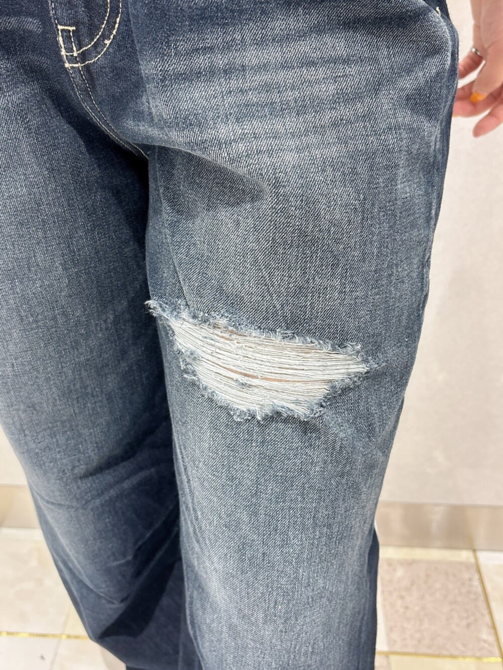 ブラック系のニット/セーター、ブルー系のデニムパンツ、ブラック系のスニーカーを着用したレディースの夏コーディネートの6枚目の写真