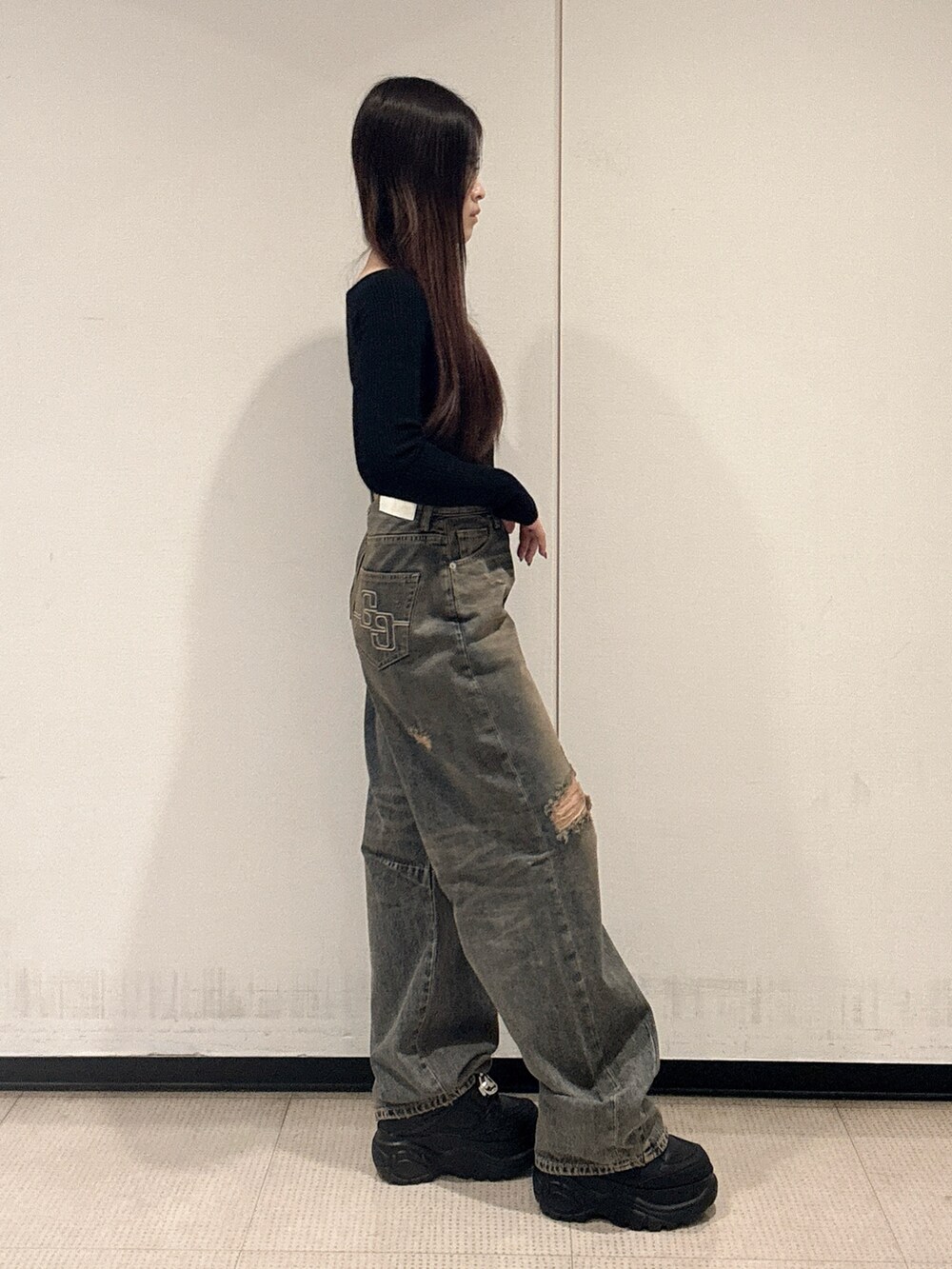 ブラック系のニット/セーター、ブルー系のデニムパンツ、ブラック系のスニーカーを着用したレディースの秋コーディネートの2枚目の写真