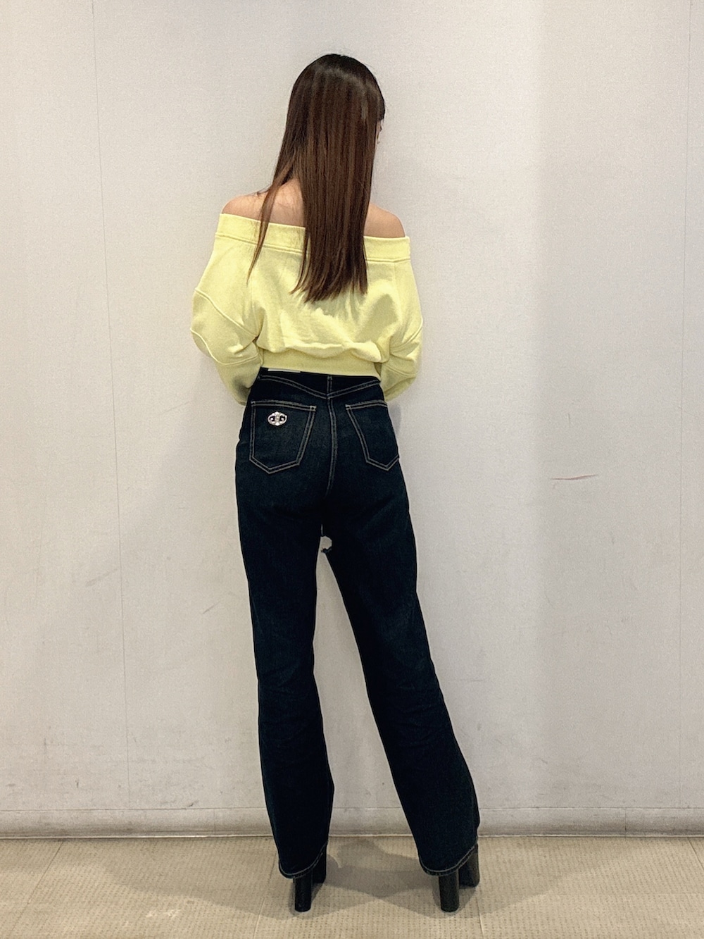 イエロー系のスウェット、ブルー系のデニムパンツ、ブラック系のブーツを着用したレディースの冬コーディネートの3枚目の写真