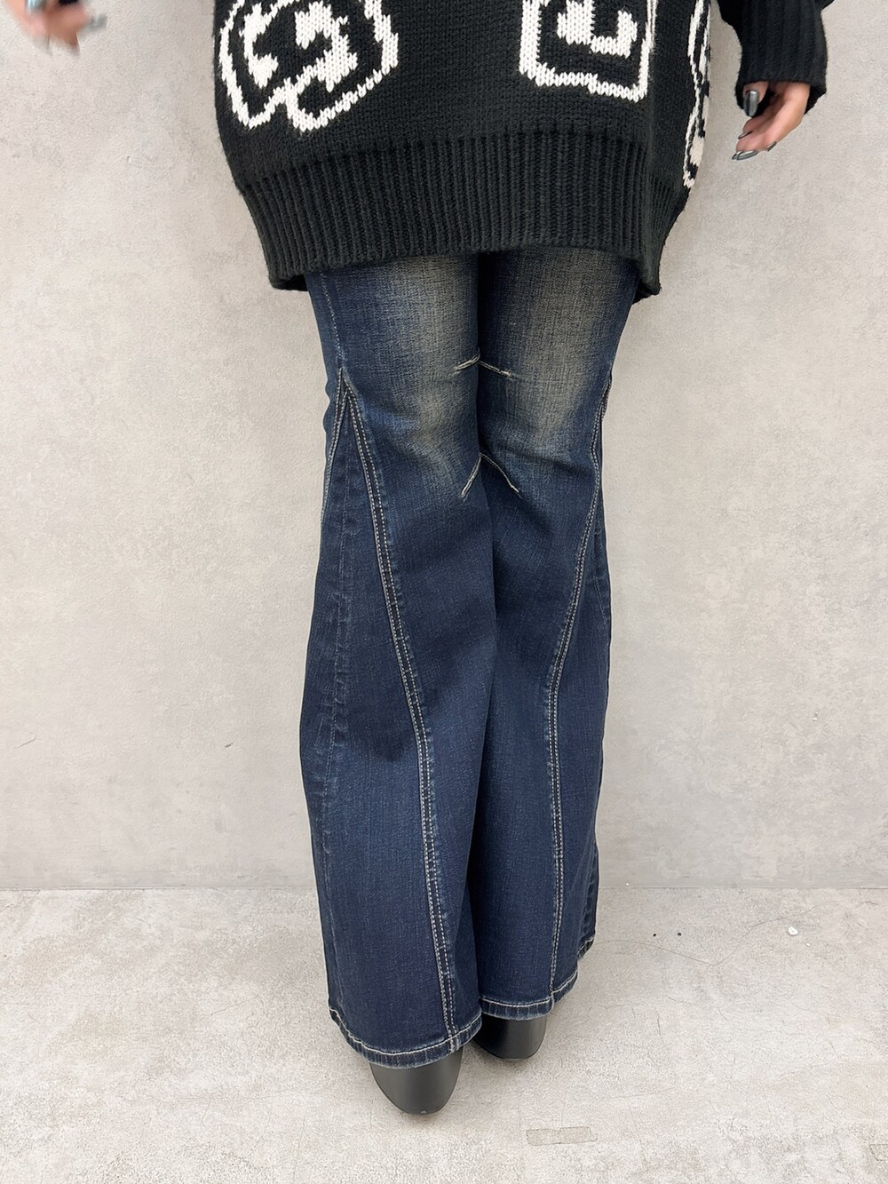 ブラック系のニット/セーター、ブルー系のデニムパンツ、ブラック系のブーツを着用したレディースの秋コーディネートの6枚目の写真