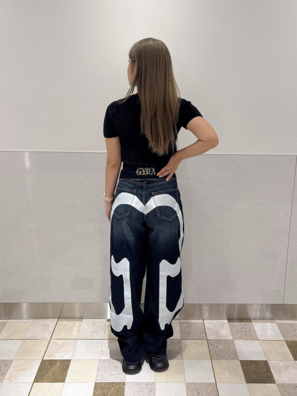 ブラック系のニット/セーター、ブルー系のデニムパンツ、ブラック系のスニーカーを着用したレディースの夏コーディネートの3枚目の写真