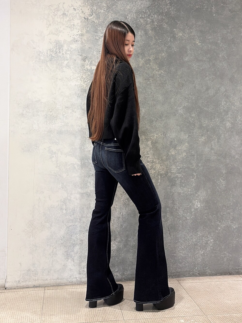 ブラック系のニット/セーター、ブルー系のデニムパンツ、ブラック系のブーツを着用したレディースの冬コーディネートの2枚目の写真