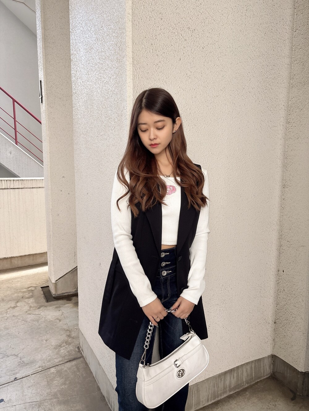 ホワイト系のTシャツ/カットソー、ブラック系のベスト、ブルー系のデニムパンツを着用したレディースの春コーディネートの4枚目の写真