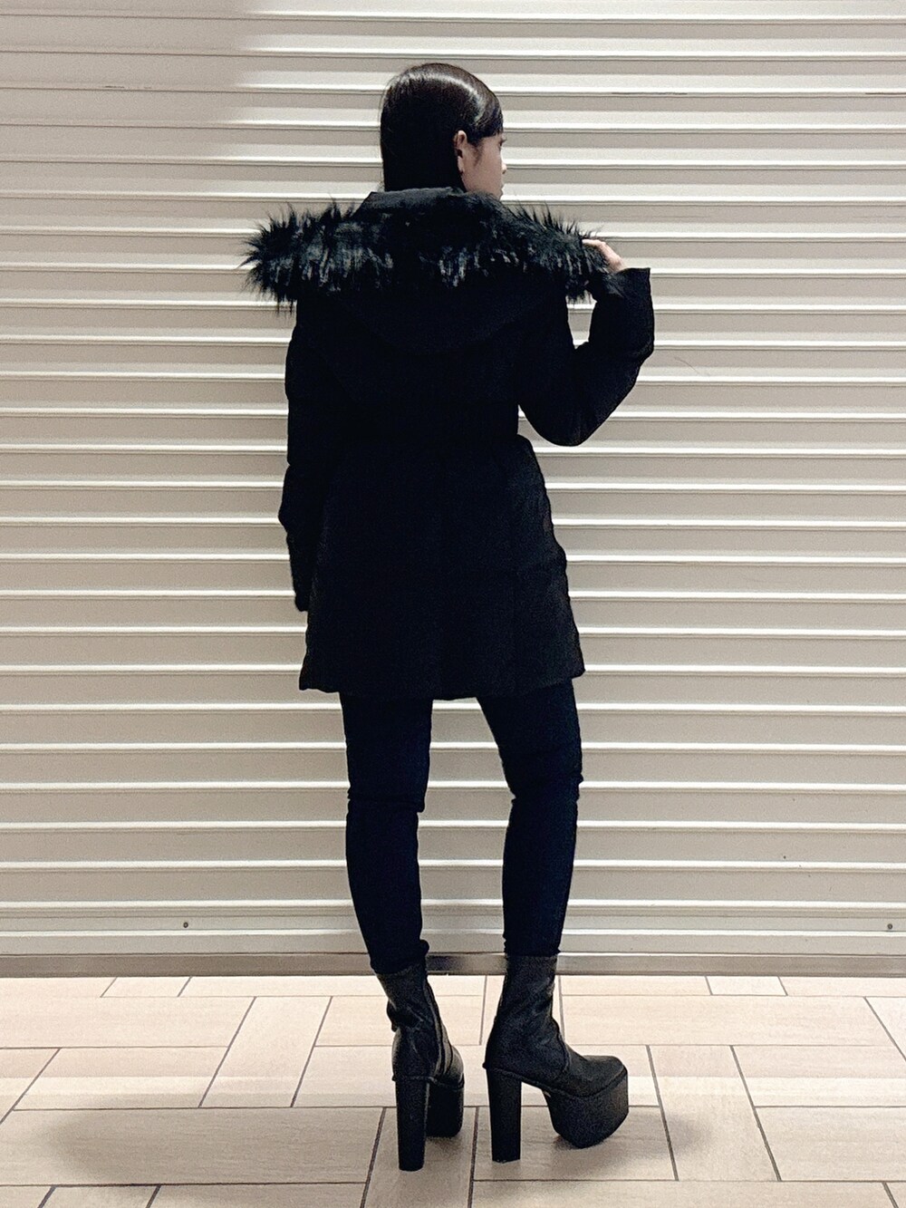 ブラック系のニット/セーター、ブラック系のダウンジャケット/コート、ブルー系のデニムパンツを着用したレディースの秋コーディネートの4枚目の写真