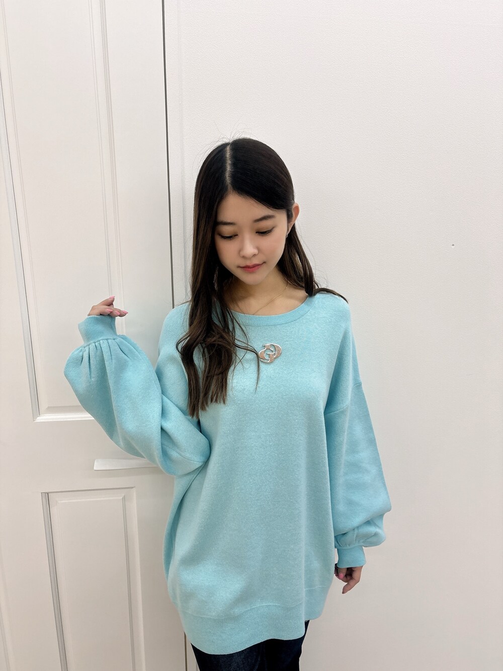 ブルー系のニット/セーター、ブルー系のデニムパンツ、ホワイト系のパンプスを着用したレディースの冬コーディネートの4枚目の写真