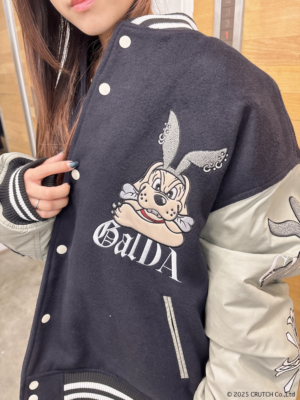 ブラック系のスタジャン、ホワイト系のニット/セーター、ブルー系のデニムパンツを着用したレディースの秋コーディネートの6枚目の写真