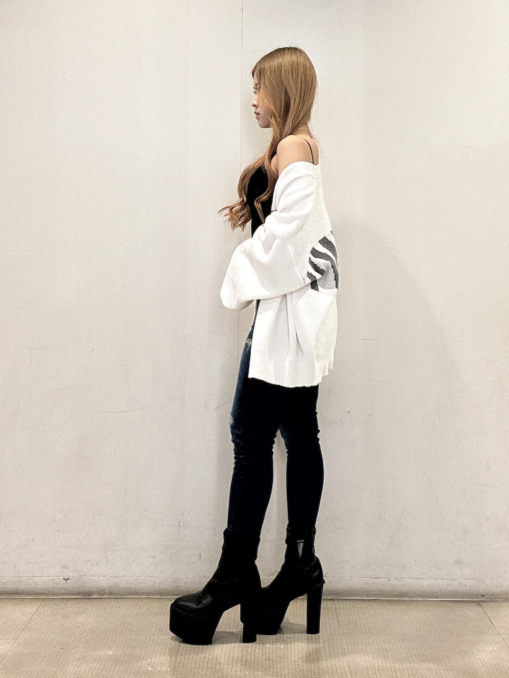 ブラック系のキャミソール、ホワイト系のカーディガン/ボレロ、ブルー系のデニムパンツを着用したレディースの春コーディネートの2枚目の写真