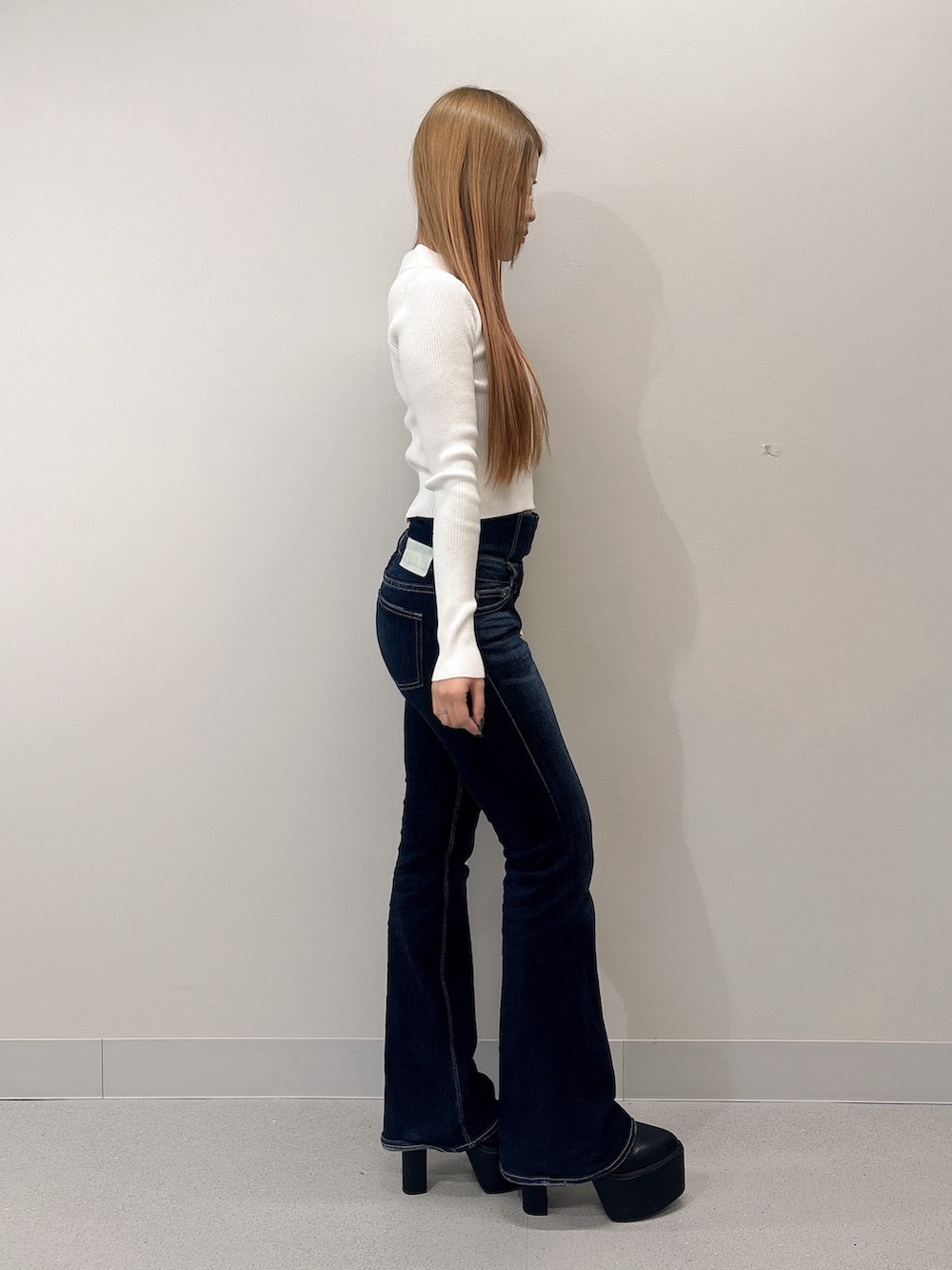 ホワイト系のニット/セーター、ブルー系のデニムパンツ、ブラック系のブーツを着用したレディースの春コーディネートの2枚目の写真