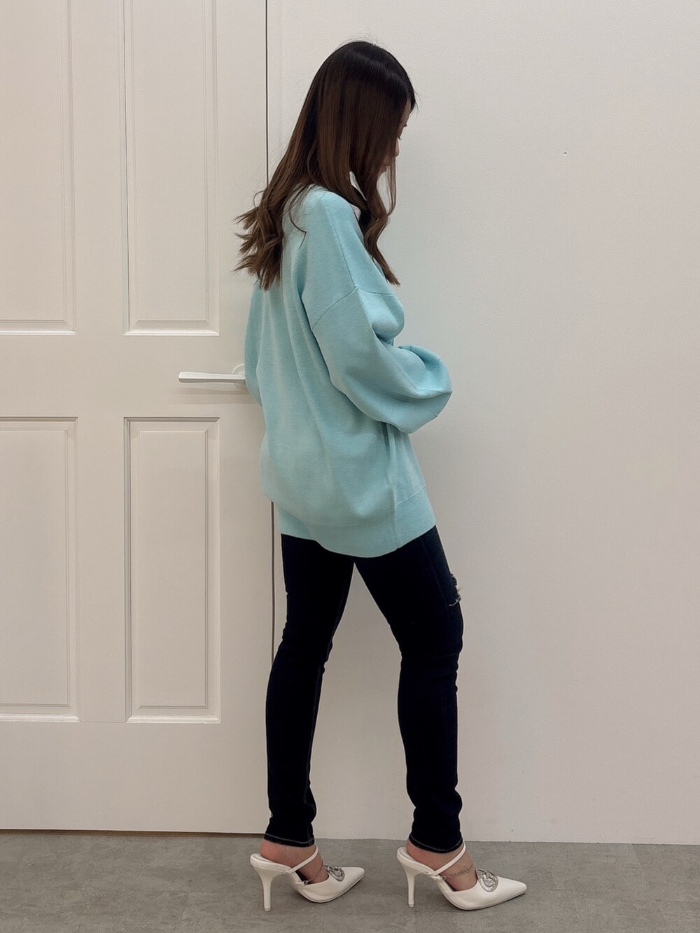 ブルー系のニット/セーター、ブルー系のデニムパンツ、ホワイト系のパンプスを着用したレディースの冬コーディネートの2枚目の写真