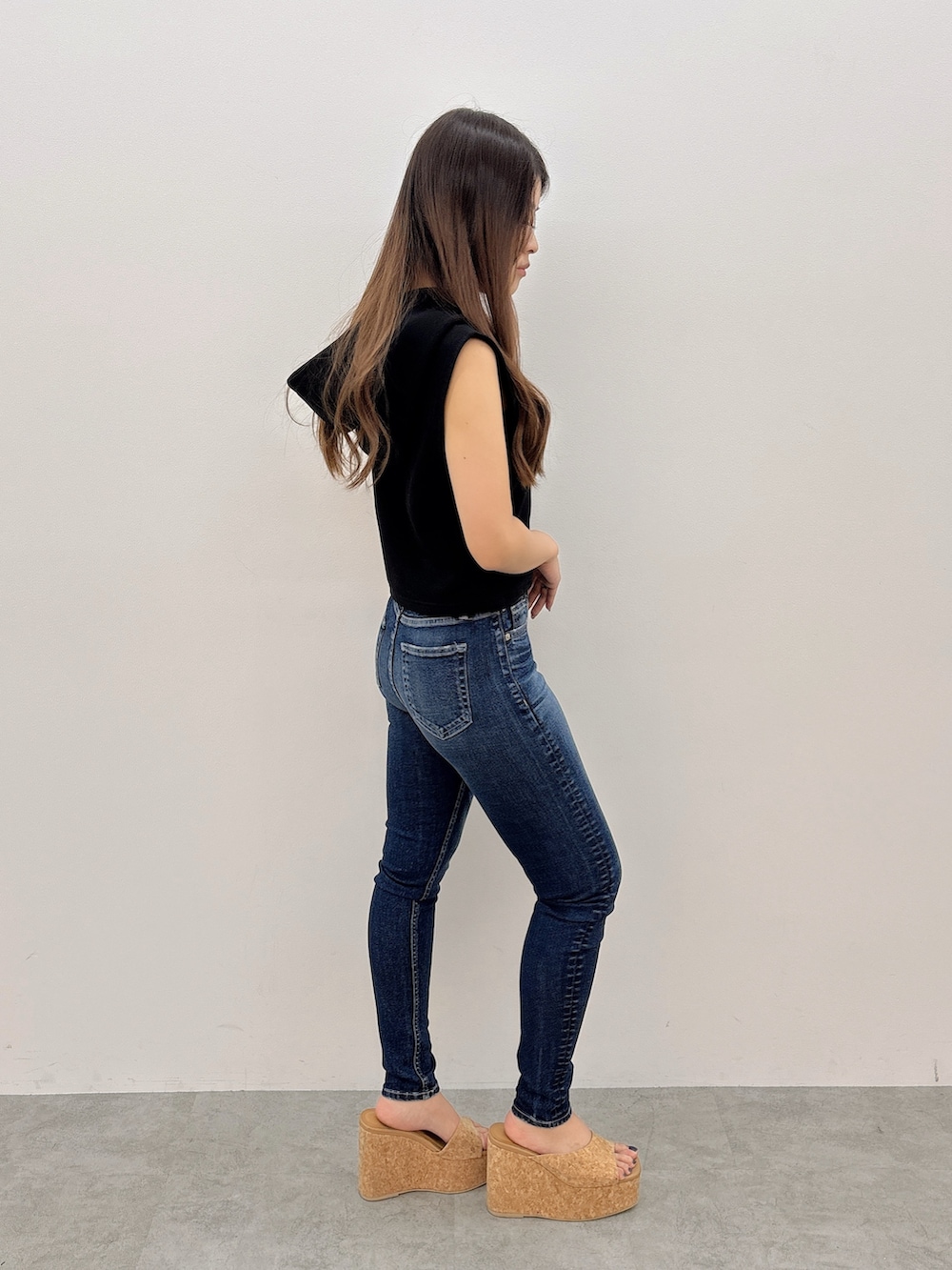 ブラック系のパーカー、ブルー系のデニムパンツ、ベージュ系のサンダルを着用したレディースの夏コーディネートの2枚目の写真