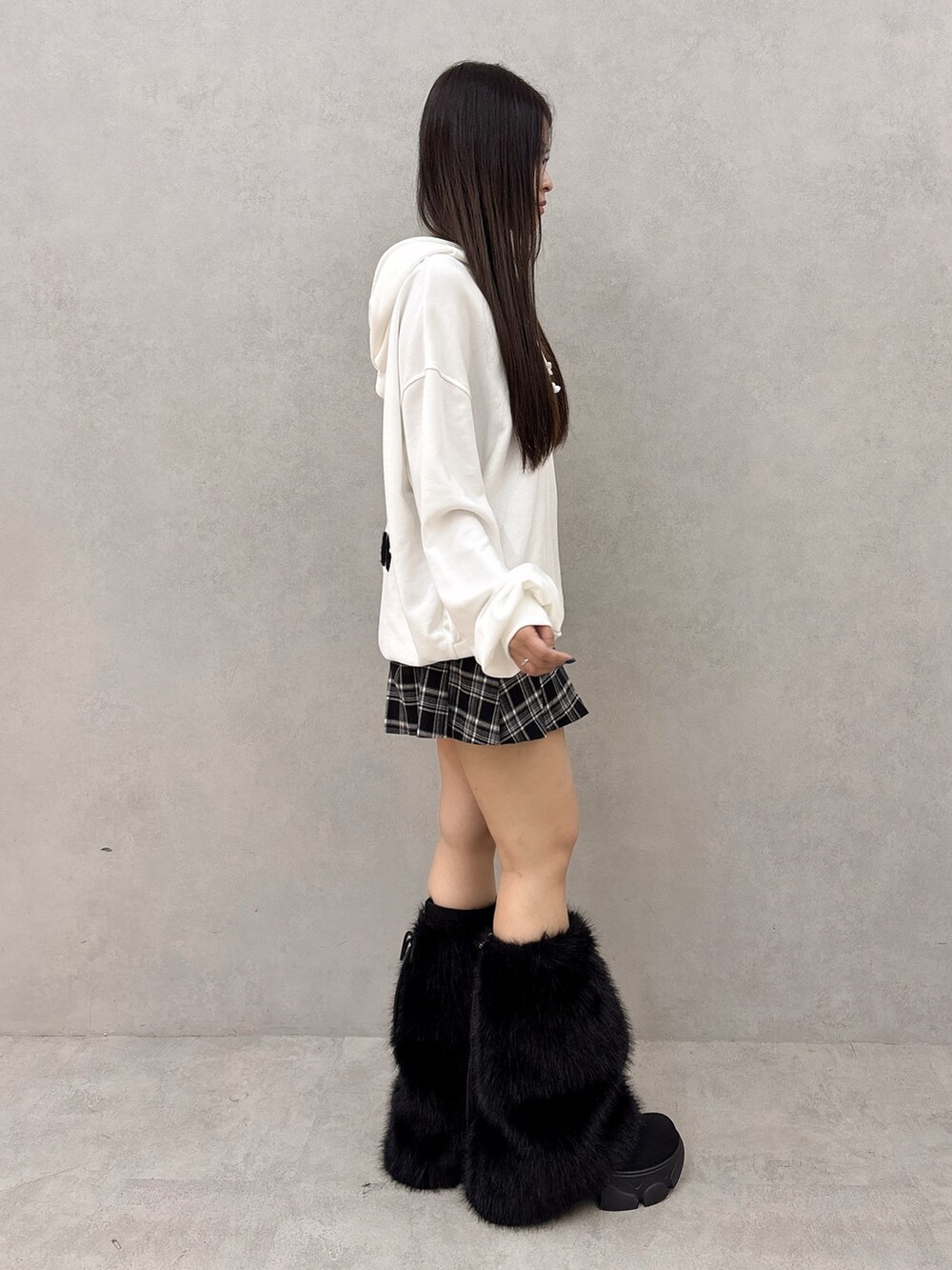 ホワイト系のパーカー、ブラック系のスカート、ブラック系のブーツを着用したレディースの秋コーディネートの2枚目の写真