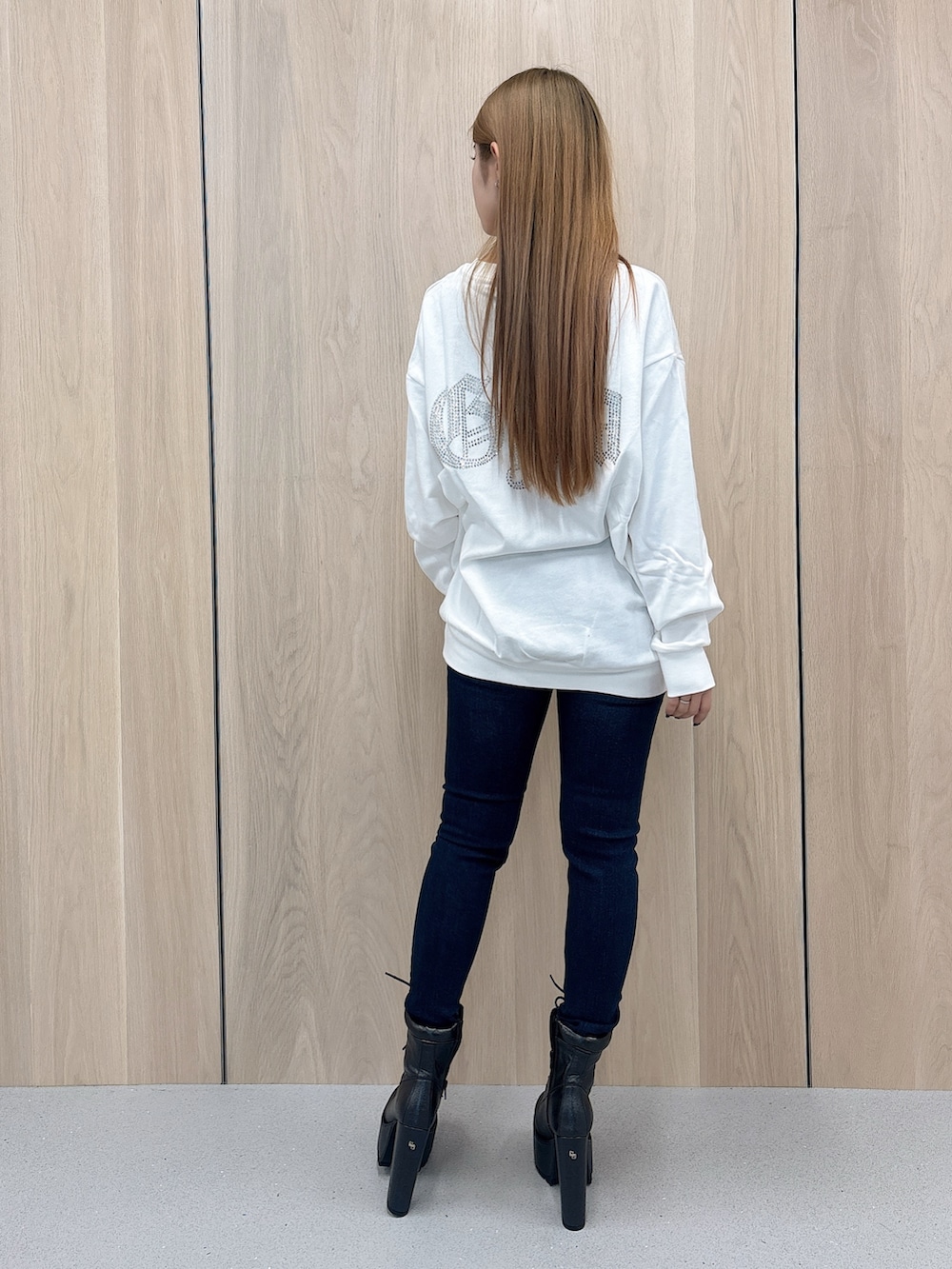 ホワイト系のパーカー、ブルー系のデニムパンツ、ブラック系のブーツを着用したレディースの春コーディネートの3枚目の写真