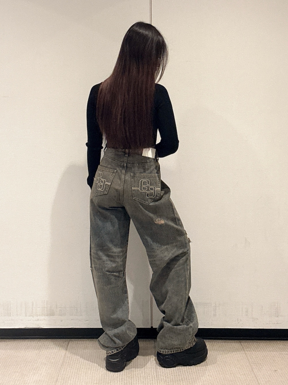 ブラック系のニット/セーター、ブルー系のデニムパンツ、ブラック系のスニーカーを着用したレディースの秋コーディネートの3枚目の写真