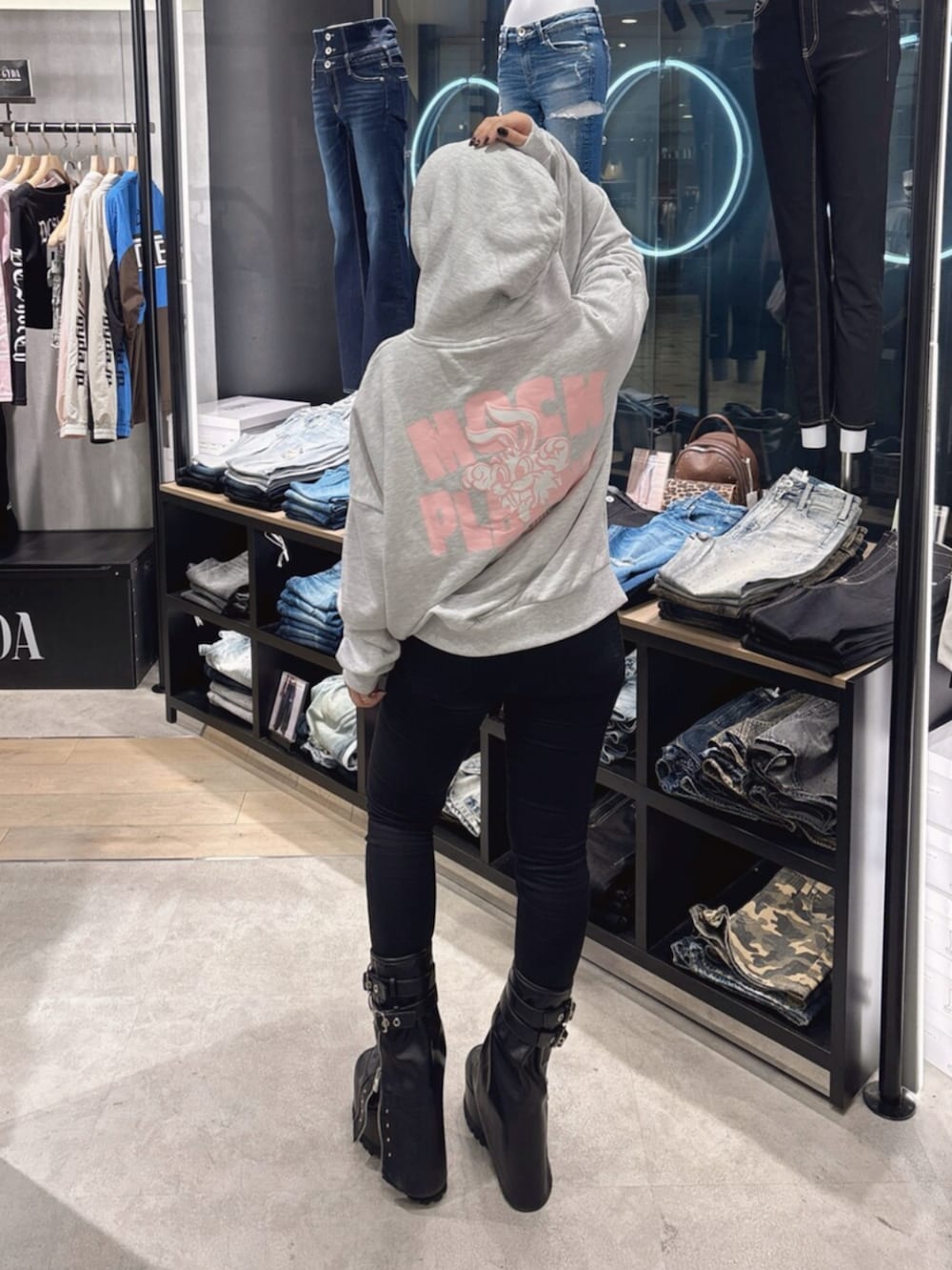 ブラック系のデニムパンツ、ブラック系のブーツ、グレー系のパーカーを着用したレディースの秋コーディネートの4枚目の写真