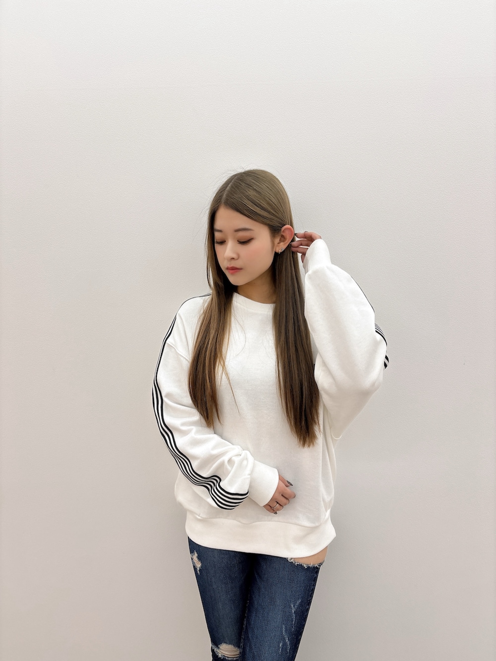 ホワイト系のスウェット、ブルー系のデニムパンツ、ブラック系のブーツを着用したレディースの冬コーディネートの4枚目の写真