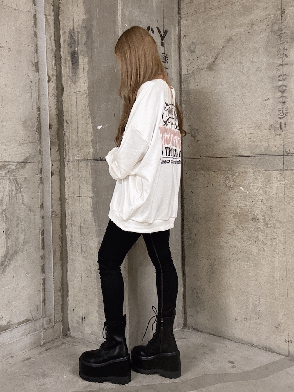 ホワイト系のスウェット、ブラック系のデニムパンツ、ブラック系のブーツを着用したレディースの秋コーディネートの2枚目の写真